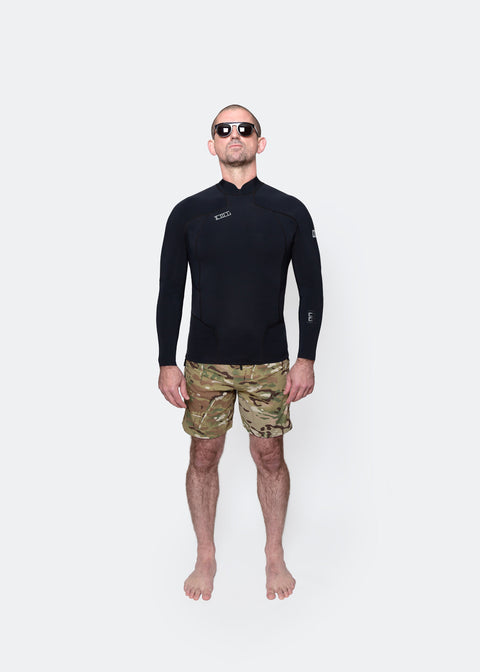 Man wearing a black 00 BY XIIIG Shinobi 1mm wetsuit jacket and camouflage boardshorts on a white background