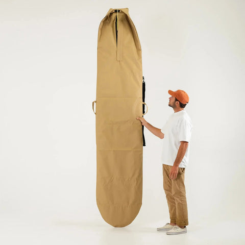 Man holding a large beige 9ft surfboard bag vertically on a white background