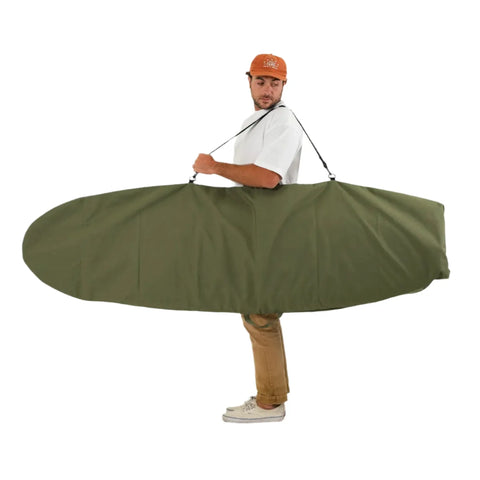 Man carrying a large green surfboard bag on a white background