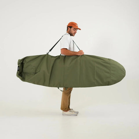 Man carrying a green surfboard bag on a white background