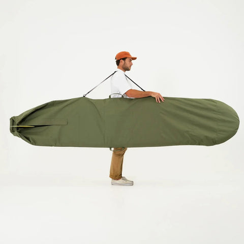 Person holding a large green surfboard bag on a white background