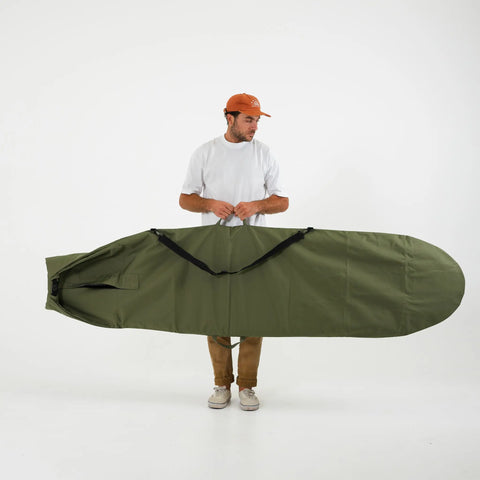 Person holding a large green surfboard bag on a white background