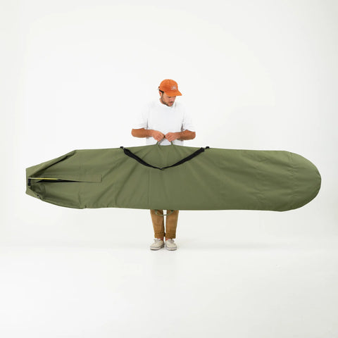 Person holding a large green surfboard bag against a white background