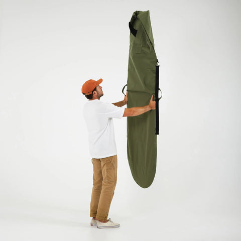 Man holding a green surfboard bag on a white background