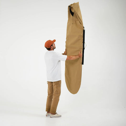 Person holding a large beige bag against a white background