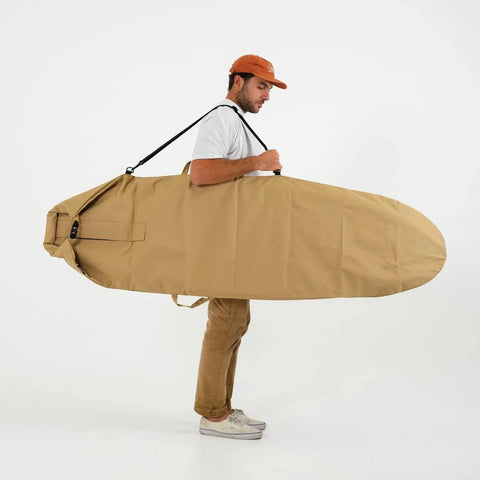 Man holding a tan 6ft surfboard bag against a white background