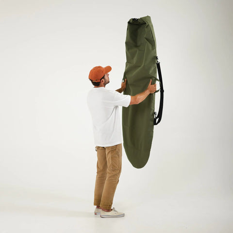 Man holding a green surfboard bag on a white background