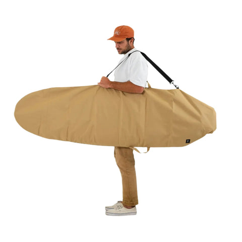 Man holding a large beige surfboard bag on a white background
